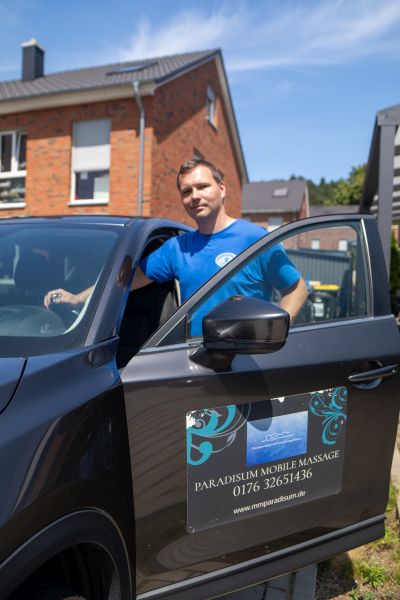 Pawel von Paradisum Massage in Geesthacht neben dem Auto mit Werbemagnet – mobile Massage direkt zu Ihnen nach Hause oder ins Büro.
