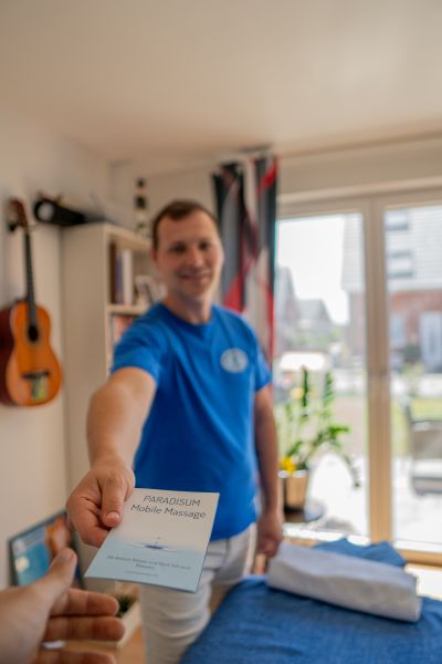 Pawel von Paradisum Massage in Geesthacht präsentiert die Informationsbroschüre – professionelle Massagen für Entspannung und Wohlbefinden.
