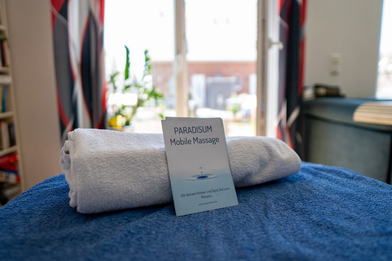Informationsbroschüre von Paradisum Massage in Geesthacht auf einem Massage-Handtuch – mobile und Praxis-Massagen für Entspannung und Wohlbefinden.