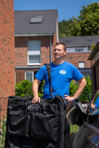 Pawel von Paradisum Massage in Geesthacht trägt ein mobiles Massageliege – flexible Massage direkt zu Ihnen nach Hause oder ins Büro.
